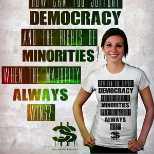 May include: A white t-shirt with black text that reads "How can you support democracy and the rights of minorities? When the majority always wins?" The text is repeated on the shirt. The shirt is being worn by a person with brown hair and a white background.