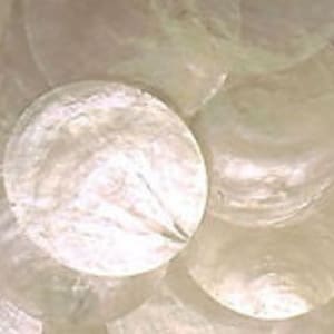 May include: A collection of multiple clear, circular glass discs stacked together. Each disc features a smooth, transparent surface with a reflective quality, showing subtle internal textures and light refraction across the layered, round glass pieces.