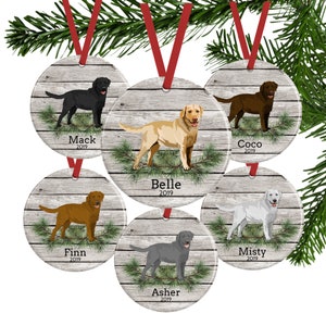 May include: Six round, whitewashed wood, Christmas ornaments with a pine bough design. Each ornament features a different Labrador Retriever breed, including black, yellow, chocolate, and white. The ornaments are personalized with the dog's name and the year 2019.