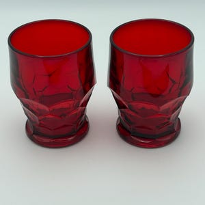 May include: Two red glass tumblers with a textured, diamond-shaped pattern.