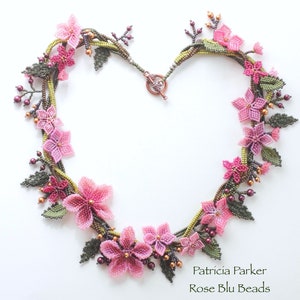May include: A delicate beaded necklace featuring pink and green flowers, with a copper clasp. The necklace is made by Patricia Parker, Rose Blu Beads.