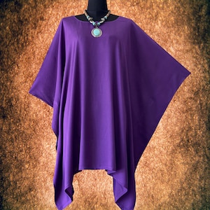 Può includere: Un top viola ampio in stile halter con una collana rotonda con un ciondolo turchese.