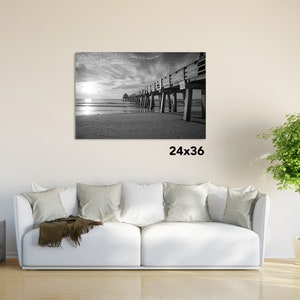 Puede incluir: Fotograf&iacute;a en blanco y negro de un muelle de madera que se extiende hacia el oc&eacute;ano. El muelle tiene una barandilla y est&aacute; sostenido por pilotes de madera. El cielo est&aacute; nublado y el agua est&aacute; tranquila. La imagen mide 61 cm por 91 cm.
