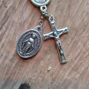 Op de afbeelding: Zilveren rozenkrans met een zilveren kruisbeeld, een zilveren medaille van de Maagd Maria en een zilveren medaille van Moeder Teresa. De medailles hebben inscripties in het Engels.