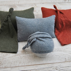 Peut inclure: Quatre bonnets pour nouveau-nés de différentes couleurs : vert, gris, bleu et orange. Les bonnets sont faits d’un tissu doux et extensible et ont un nœud sur le dessus.