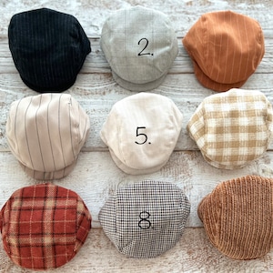 Puede incluir: Se muestran nueve gorras de estilo newsboy en varios colores y patrones. Las gorras incluyen rayas negras, cuadros grises, rayas óxido, rayas beige, crema, cuadros beige, cuadros rojos, pata de gallo en blanco y negro y pana marrón.