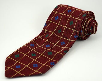 May include: A burgundy tie with a geometric pattern of yellow squares and small blue and green flowers.