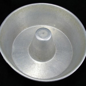 Op de afbeelding: Een zilveren metalen bundt cakevorm met een middelste buis. De vorm heeft een glad, glanzend oppervlak met wat krassen.