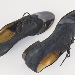 Peut inclure: Paire de chaussures &agrave; lacets en daim et cuir verni bleu marine. Les chaussures ont une pointe arrondie et un talon bas. Le nom de la marque "ANDRE" est visible sur la semelle int&eacute;rieure.