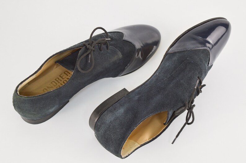 Peut inclure: Paire de chaussures &agrave; lacets en daim et cuir verni bleu marine. Les chaussures ont une pointe arrondie et un talon bas. Le nom de la marque "ANDRE" est visible sur la semelle int&eacute;rieure.