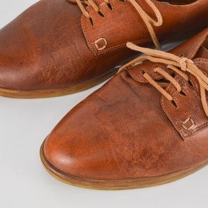 May include: A pair of brown leather lace-up shoes with a rounded toe and a low heel.