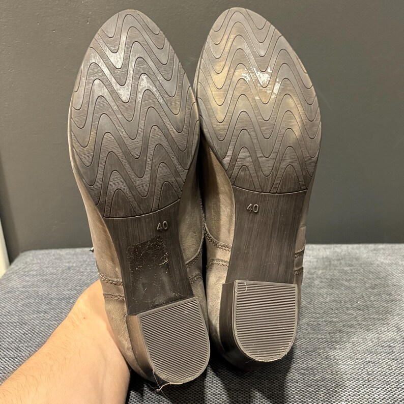 May include: A pair of gray ankle boots with a textured sole. The soles are dark brown with a wavy pattern. The heels are a low block style. The size 40 is visible on the sole.