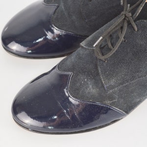 Peut inclure: Une paire de chaussures en cuir bleu marine avec une fermeture &agrave; lacets. Les chaussures ont un bout en cuir verni et une tige en daim.