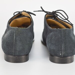 Peut inclure: Une paire de chaussures en daim noir &agrave; lacets avec des bordures blanches sur les c&ocirc;t&eacute;s. Les chaussures ont une pointe arrondie et un talon bas.