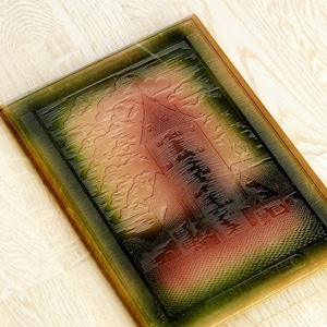 May include: A vintage, rectangular book cover with a castle design. The cover features a detailed embossed image of a castle tower, clouds, and trees. The color gradient transitions from green to brown to red. The book's edges are a darker green.
