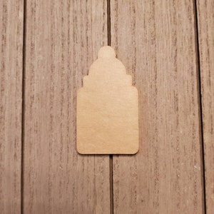 May include: A light brown wooden tag with a decorative top and a rectangular body. The tag is blank and ready for customization. The tag is set against a wooden background.