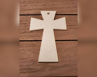 May include: A light-colored, wooden cross with a hole at the top for hanging. The cross has a simple, minimalist design with a slightly tapered base and horizontal arms. The cross is set against a brown wooden background.