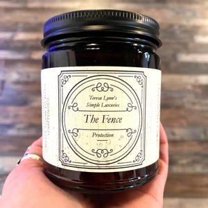 The Fence, Protection and Boundary Setting Wooden Wick Soy Wax Candle in a dark Amber jar with a metal lid, held in Teresas Hand.Cedar and Redwood cleansing and protection blessings.
Cedar wood and Redwood essential oil, when used for charms are often referred to as “The fence” due to its powerful characteristic of forcing harmful projections out and keeping protective powers in. Crafted in Monrovia, Indiana at Teresa Lynns Simple Luxuries