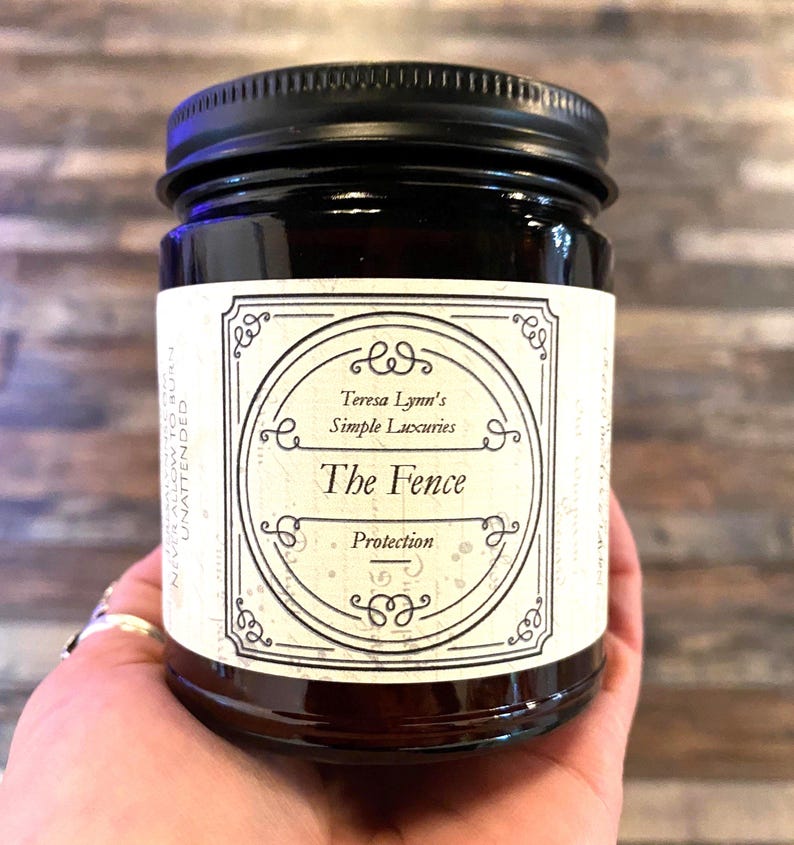 The Fence, Protection and Boundary Setting Wooden Wick Soy Wax Candle in a dark Amber jar with a metal lid, held in Teresas Hand.Cedar and Redwood cleansing and protection blessings.
Cedar wood and Redwood essential oil, when used for charms are often referred to as “The fence” due to its powerful characteristic of forcing harmful projections out and keeping protective powers in. Crafted in Monrovia, Indiana at Teresa Lynns Simple Luxuries