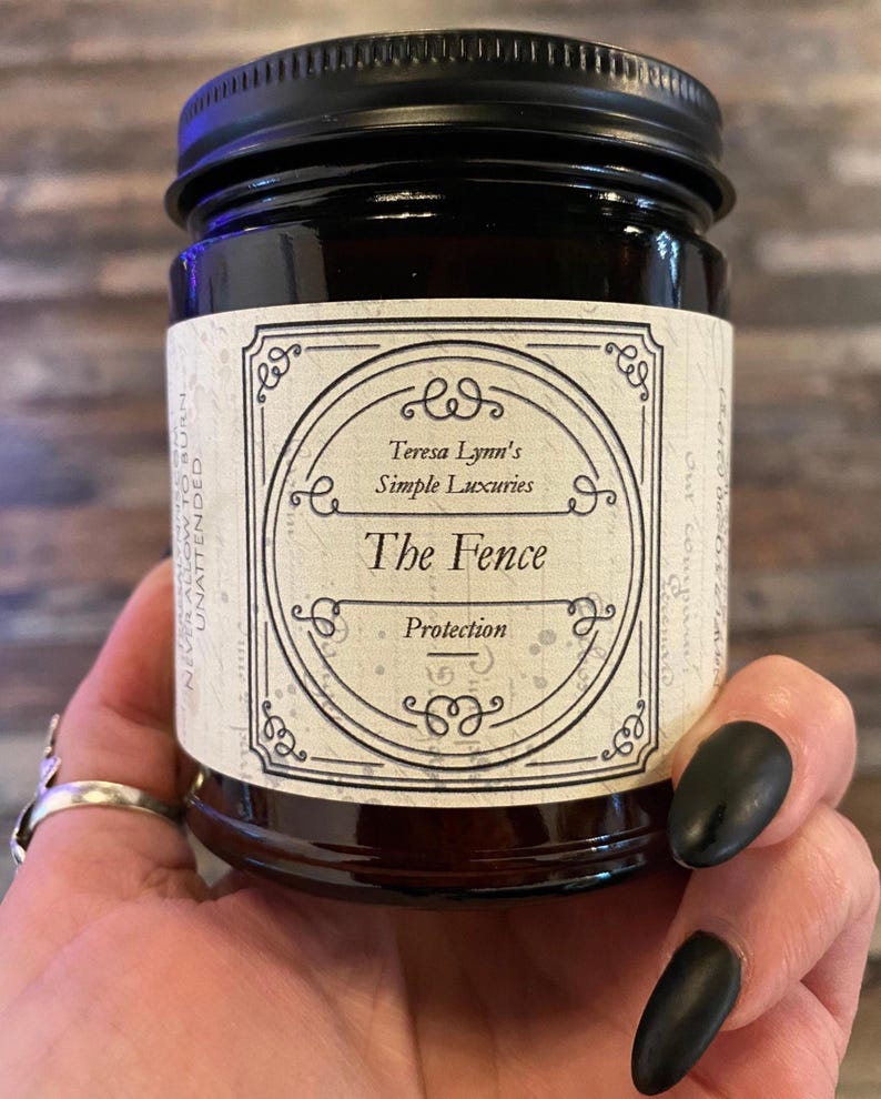 The Fence, Protection and Boundary Setting Wooden Wick Soy Wax Candle in a dark Amber jar with a metal lid, held in Teresas Hand.Cedar and Redwood cleansing and protection blessings.
Cedar wood and Redwood essential oil, when used for charms are often referred to as “The fence” due to its powerful characteristic of forcing harmful projections out and keeping protective powers in. Crafted in Monrovia, Indiana at Teresa Lynns Simple Luxuries