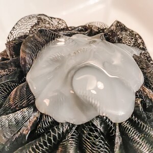 A black shower poof with a n application of thick shower gel demonstrates the thickness of this product.
