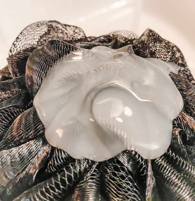 A black shower poof with a n application of thick shower gel demonstrates the thickness of this product.