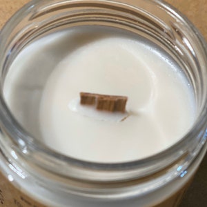 A creamy sand colored candle is photographed from above, showing a wooden wick.