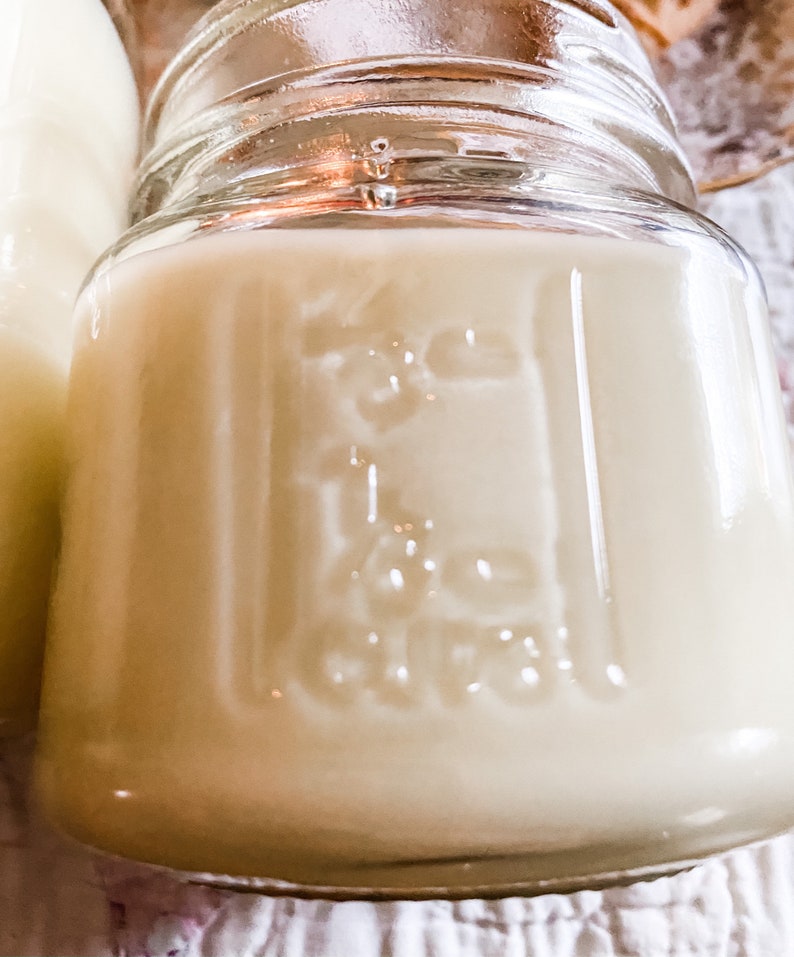 A mason jar with measuring increments filled with a sand colored candle.