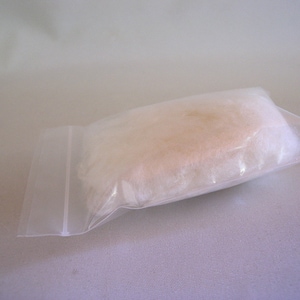 May include: A small, white, rectangular object wrapped in a clear plastic bag with a zip closure.