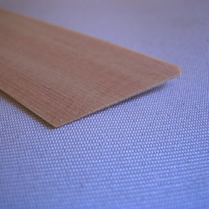 May include: A thin, light brown wooden strip with a slightly beveled edge.