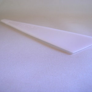 May include: A white plastic scraper tool, ideal for removing excess adhesive or smoothing out surfaces.