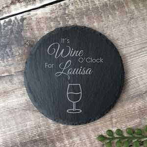 May include: Black slate coaster with the text "It's Wine O'Clock For Louisa" and a wine glass icon.