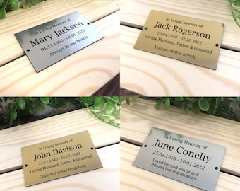 May include: Four gold and silver memorial plaques with engraved text. The plaques are rectangular and have rounded corners. The text on the plaques includes names, dates, and messages of remembrance.