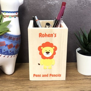 May include: A wooden pencil holder featuring a lion design. The holder is personalised with the name "Rohen's" and the text "Pens and Pencils".