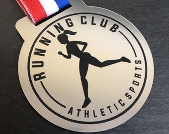 Könnte beinhalten: Silberne Laufmedaille mit einer schwarzen Silhouette einer laufenden Frau. Die Medaille trägt den Text "RUNNING CLUB ATHLETIC SPORTS" am Rand.