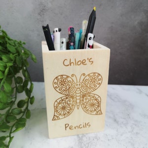 May include: A wooden pencil holder with a butterfly design and the text "Chloe's Pencils".