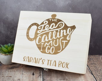 May include: A white wooden tea box with a brown silhouette of a teapot and the text "The Tea is Calling I Must Go". The box has the text "Sarah's Tea Box" on the front.