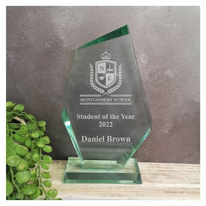 Puede incluir: Una placa de premio de vidrio verde con un escudo de armas de la escuela y el texto "Montgomery School". La placa dice "Estudiante del Año 2022 Daniel Brown".