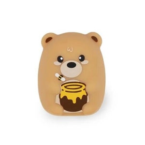 以下が含まれることがあります： ハチミツの壺を持った茶色のクマの漫画キャラクター。クマは黒い目と黒い鼻を持つかわいい顔をしています。ハチミツの壺は黄色と茶色で、側面にミツバチがいます。