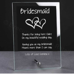 May include: A glass plaque with a white inscription that reads "Bridesmaid" with two hearts and the text "Thanks for being here Claire On my beautiful wedding day. Having you as my bridesmaid Meant more than I can say. Lots of Love Gemma x".