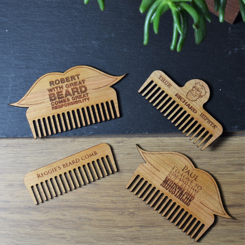 Peut inclure: Quatre peignes &agrave; barbe en bois avec texte grav&eacute;. L'un porte l'inscription "ROBERT WITH GREAT BEARD COMES GREAT RESPONSIBILITY". Un autre dit "TRUE RICHARD HIPSTA". Le troisi&egrave;me dit "REGGIE'S BEARD COMB". Le dernier dit "PAUL I'D LOVE TO STAY AND CHAT BUT I REALLY MOUSTACHE".