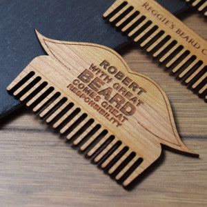Peut inclure: Peigne &agrave; barbe en bois avec une poign&eacute;e en forme de moustache. Le peigne est grav&eacute; des mots "ROBERT WITH GREAT BEARD COMES GREAT RESPONSIBILITY". Le peigne est de couleur brun clair et poss&egrave;de des dents fines.