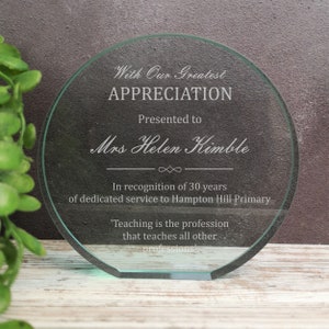 May include: A round, clear glass plaque with a white inscription. The inscription reads "With Our Greatest Appreciation Presented to Mrs Helen Kimble In recognition of 30 years of dedicated service to Hampton Hill Primary 'Teaching is the profession that teaches all other professions'"