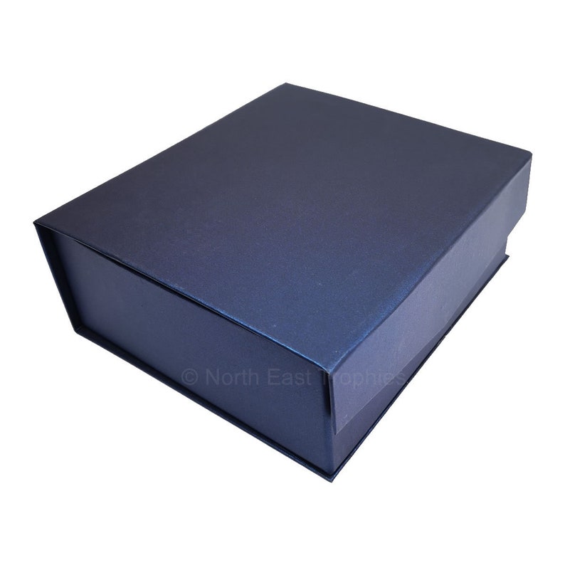 May include: A dark blue, rectangular gift box with a smooth, textured surface. The box is closed and has a flap on the top.