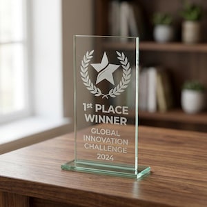 Peut inclure: Troph&eacute;e en verre transparent avec une &eacute;toile et une couronne de laurier. Le texte indique "1st PLACE WINNER GLOBAL INNOVATION CHALLENGE 2024". Le troph&eacute;e rectangulaire est pos&eacute; sur une base rectangulaire, sur une table en bois.