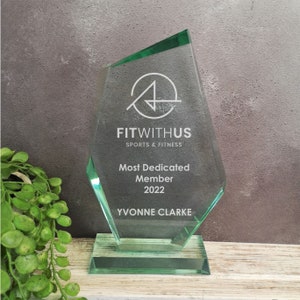 May include: A green glass award with the text "FITWITHUS SPORTS & FITNESS" and "Most Dedicated Member 2022 YVONNE CLARKE" on it.