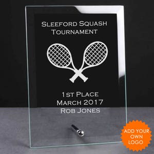 Könnte beinhalten: Eine Glasplakette mit schwarzem Hintergrund und weißem Text. Der Text lautet "Sleeford Squash Tournament", "1st Place", "March 2017" und "Rob Jones". Die Plakette zeigt eine weiße Silhouette von zwei gekreuzten Tennisschlägern.