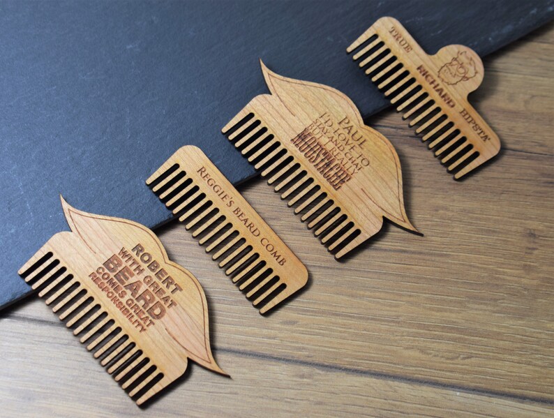 Peut inclure: Quatre peignes &agrave; barbe en bois avec texte grav&eacute;. L'un d'eux porte l'inscription "TRUE RICHARD HIPSTA" avec une petite illustration. Un autre dit "PAUL I'D LOVE TO STAY AND CHAT BUT I REALLY MOUSTACHE". Le troisi&egrave;me dit "REGGIE'S BEARD COMB". Le dernier dit "ROBERT WITH GREAT BEARD COMES GREAT RESPONSIBILITY".