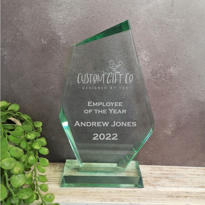May include: A green glass award plaque with the text "CUSTOM GIFT CO DESIGNED BY YOU" and "EMPLOYEE OF THE YEAR ANDREW JONES 2022".