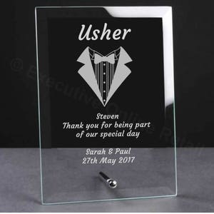 May include: A glass plaque with a tuxedo graphic and the text "Usher" at the top. The plaque also includes the text "Steven, Thank you for being part of our special day, Sarah & Paul, 27th May 2017".